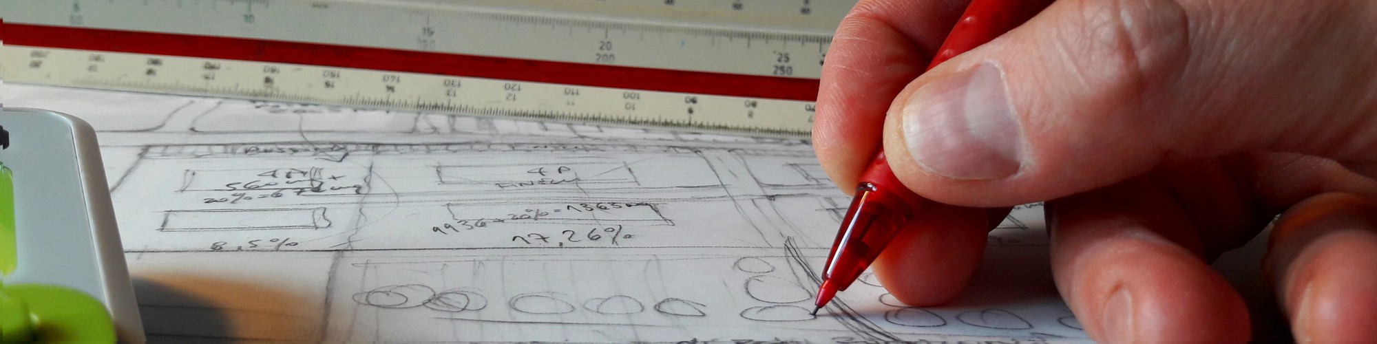 Bild: Hand mit Stift und Maßstabslinieal auf Bauzeichnung